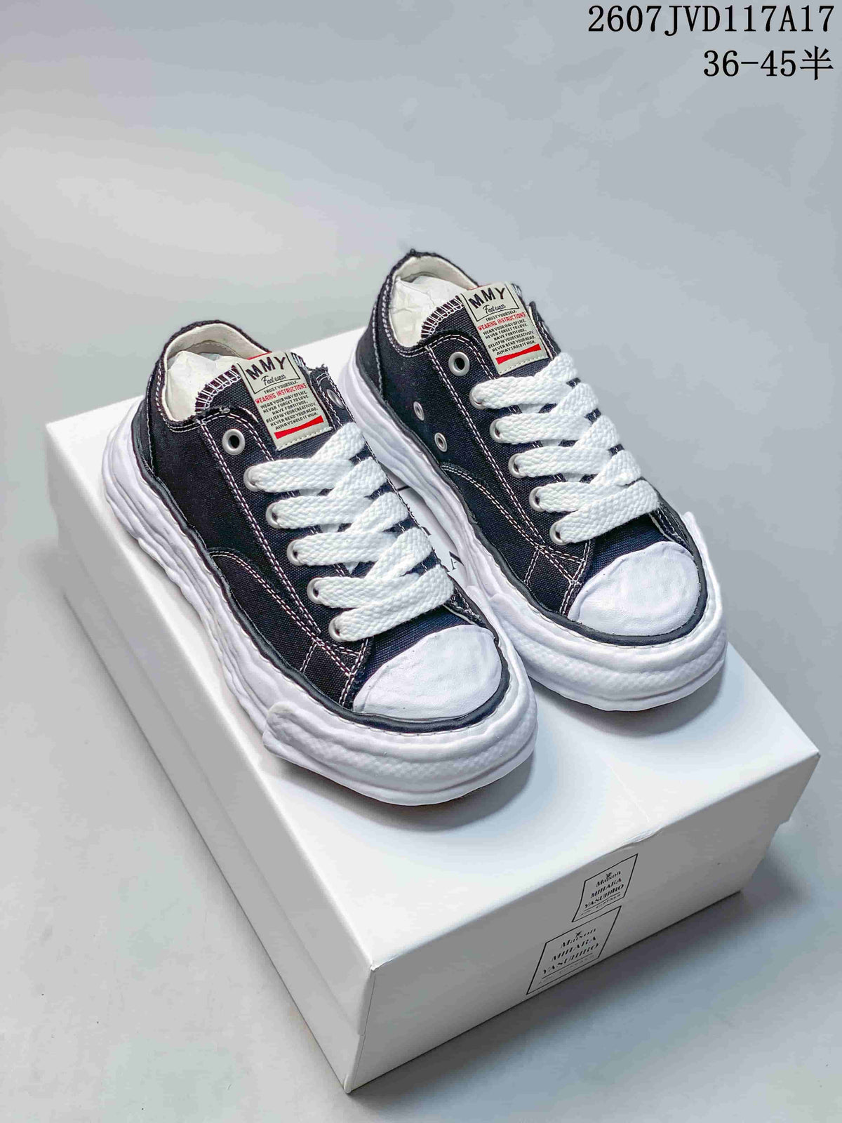 Black MMY low-top canvas sneakers with white laces and a sculpted white sole displayed on a shoebox.
