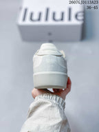 Rear view of the white sneaker showing the padded heel area, tonal logo detail, and textured rubber outsole.