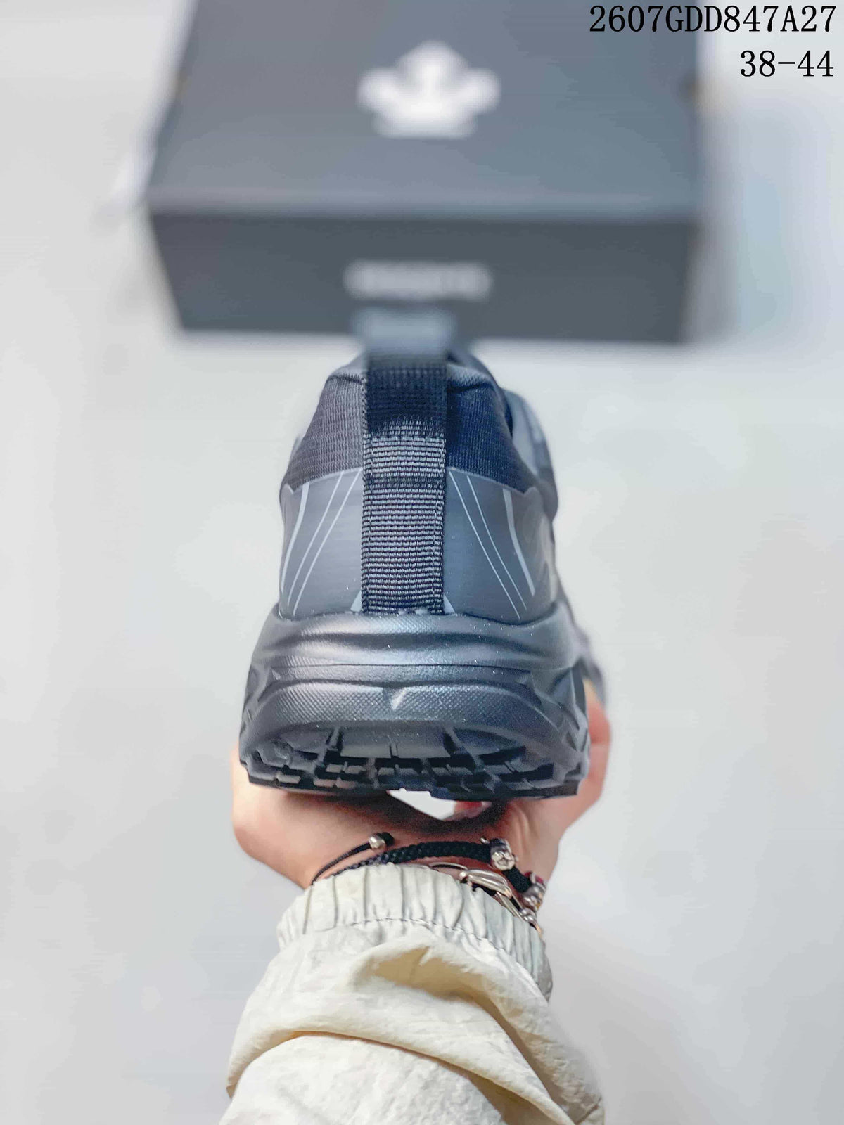 Rear view of a black sneaker showing the heel pull tab, reflective-style panel lines, and outsole.