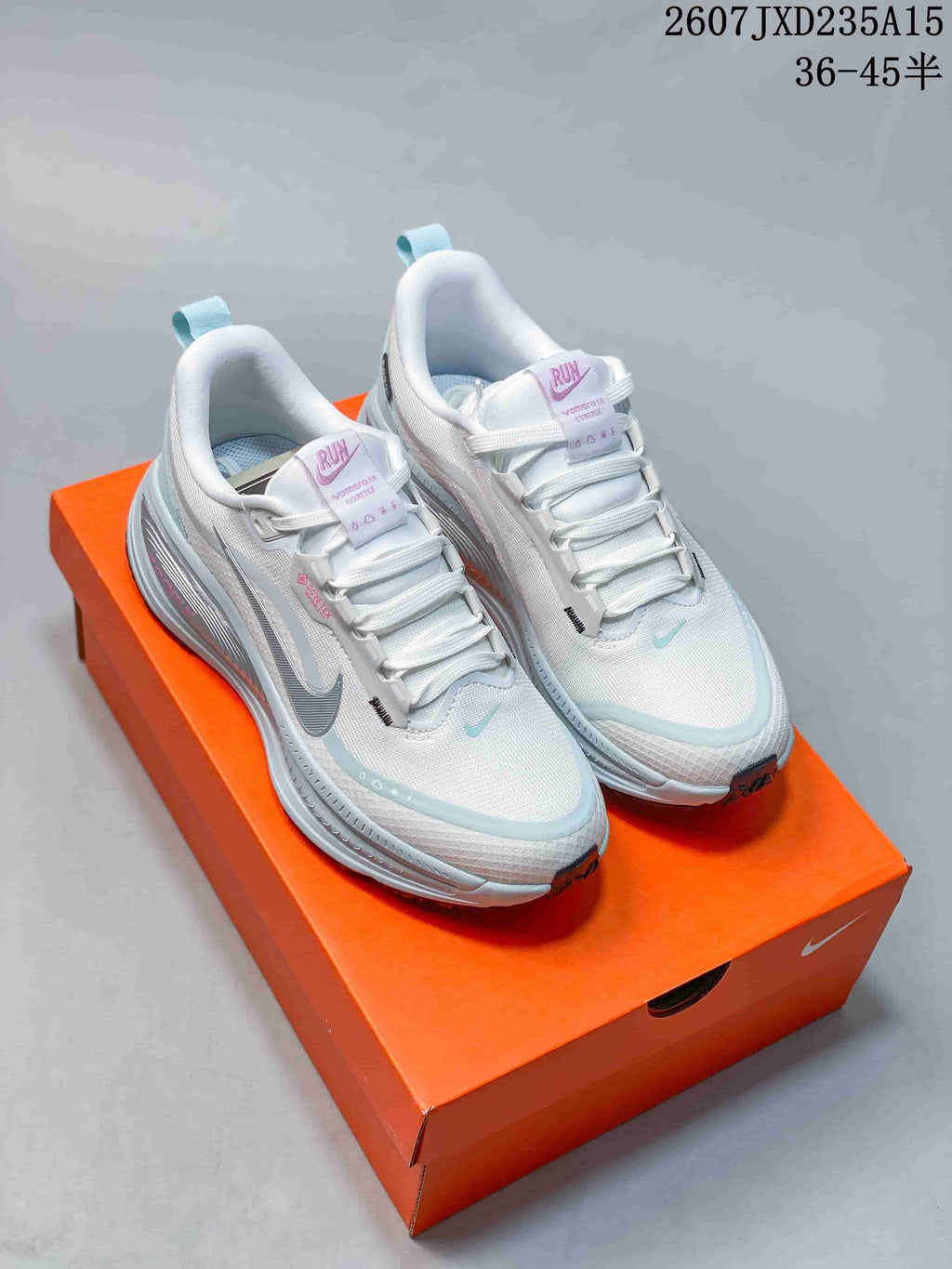 Pair of white and light-blue Nike running shoes displayed on an orange shoebox.