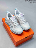 Pair of white and light-blue Nike running shoes displayed on an orange shoebox.