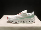 Full side profile of one white On Cloudmonster 1 sneaker with pale green heel detail and a segmented outsole.