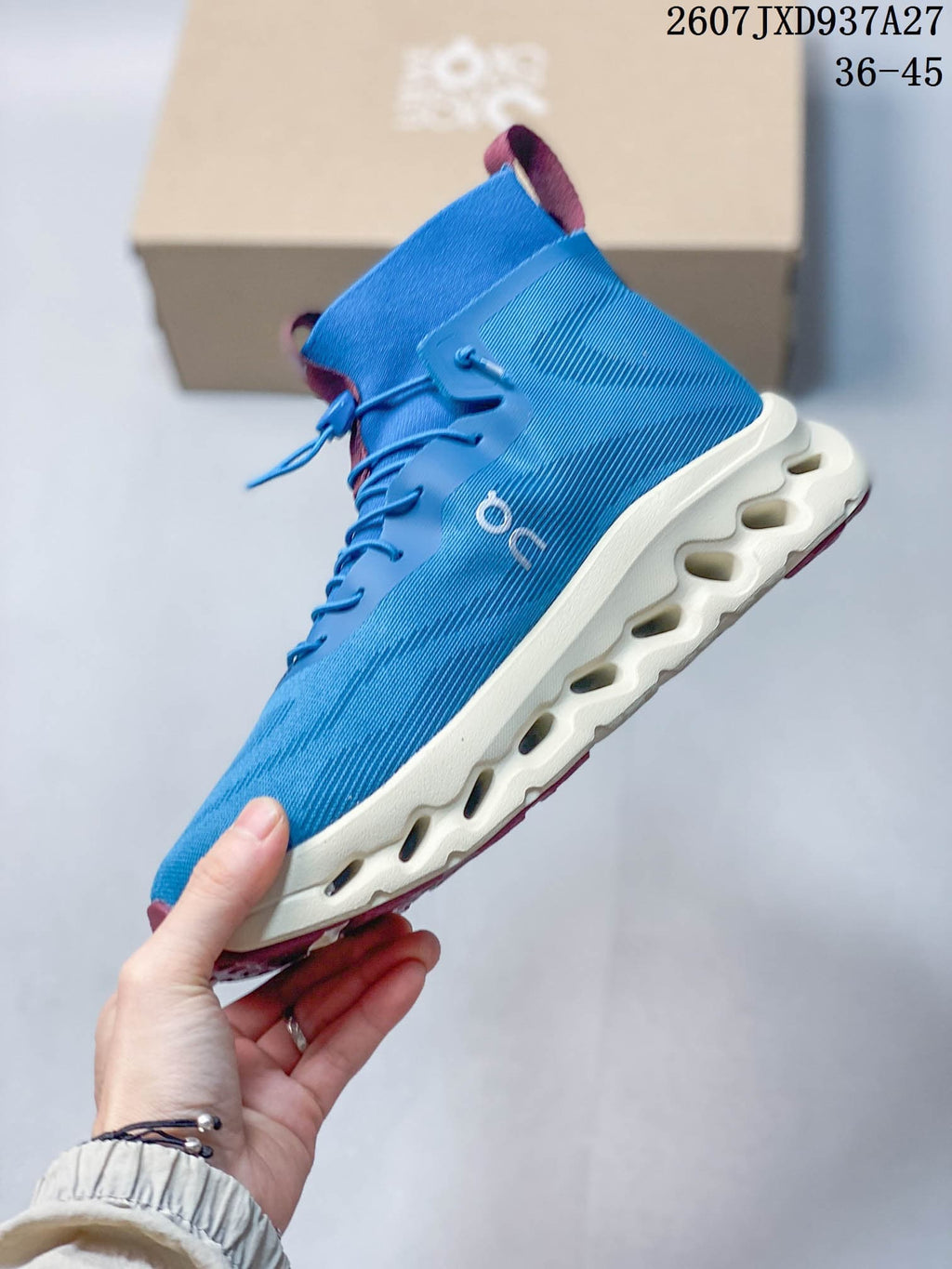 Side profile showing the blue upper, On branding, burgundy outsole accents and sculpted white sole.