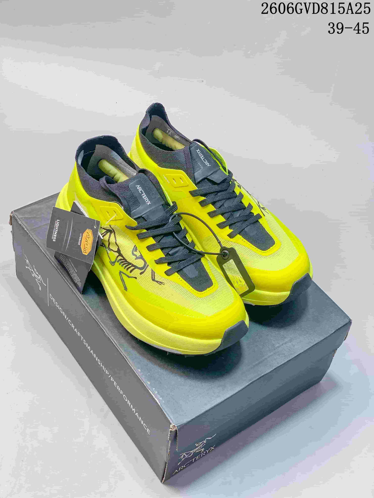 Pair of neon yellow and dark gray Arc'teryx Norvan SY trail shoes on a shoebox