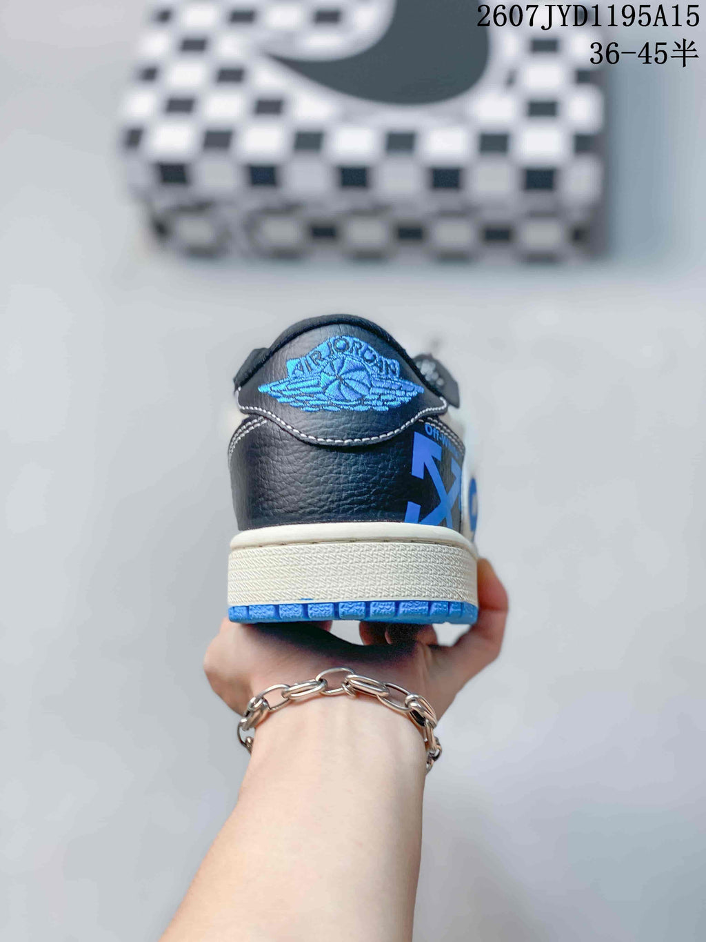Rear view of the sneaker showing black heel panels, blue outsole edging, and a blue wing-style logo detail.