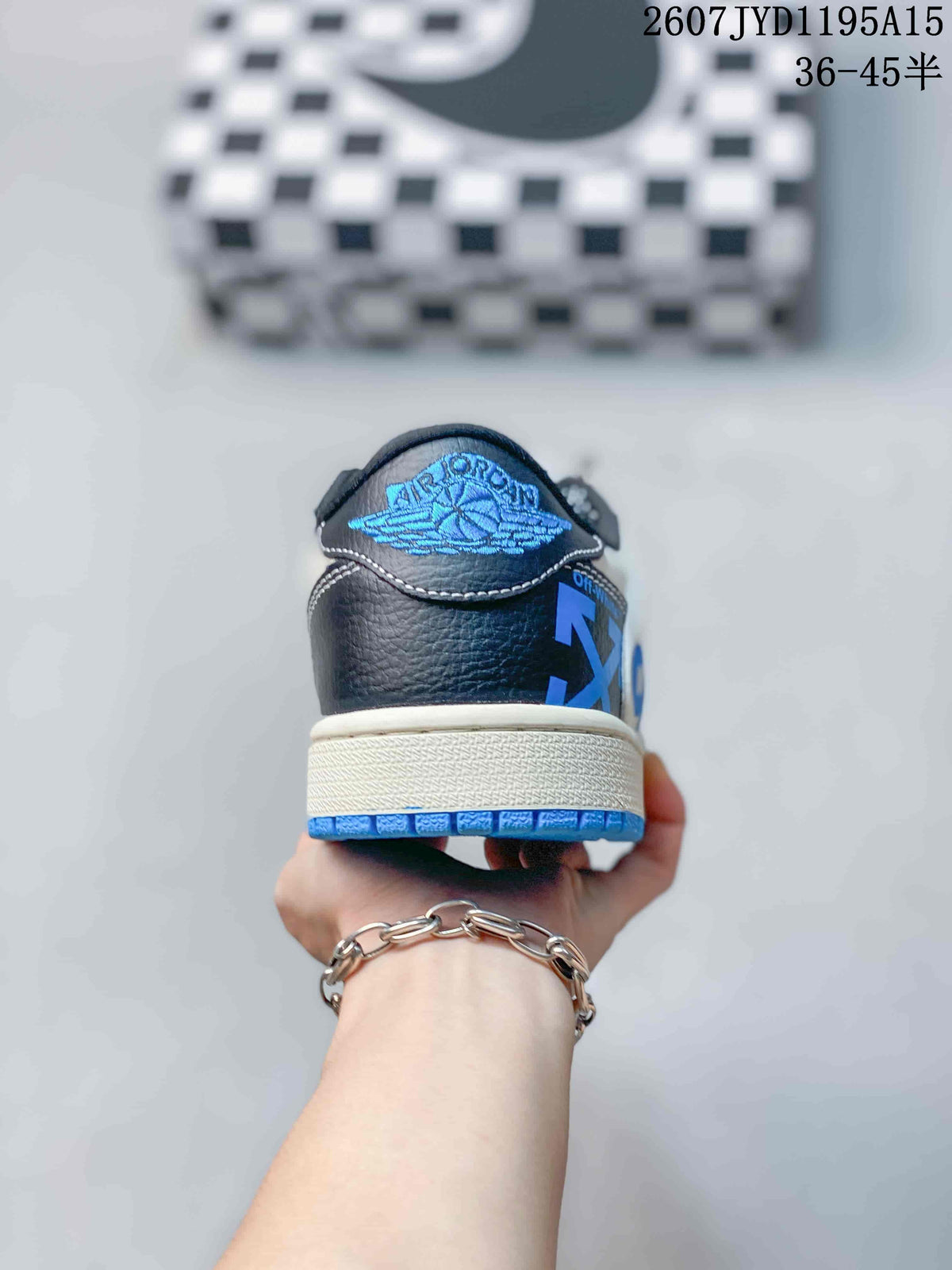 Rear view of the sneaker showing black heel panels, blue outsole edging, and a blue wing-style logo detail.