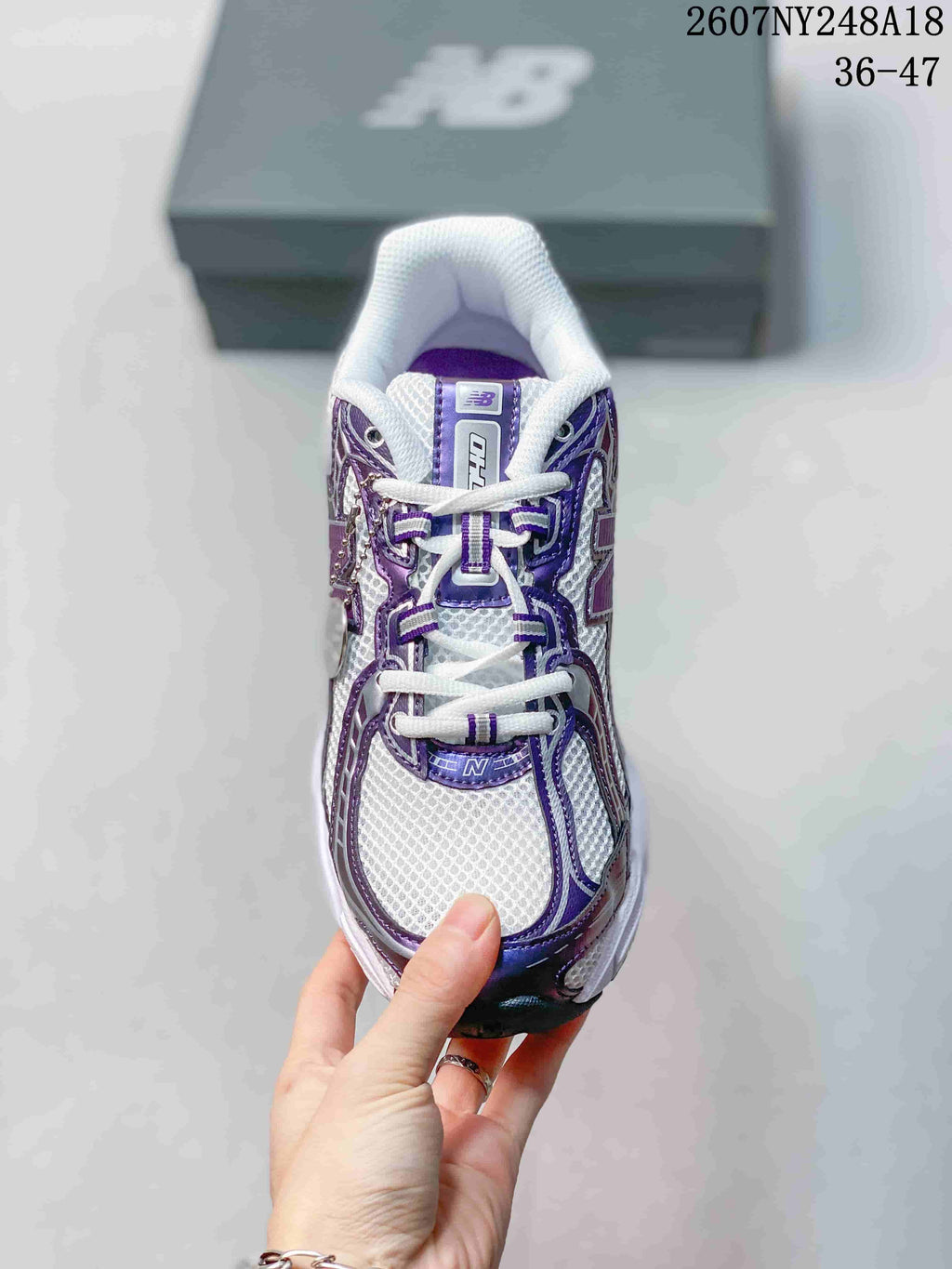 Top view of the white and purple New Balance sneaker showing the laces, mesh-like toe panel, and tongue branding.