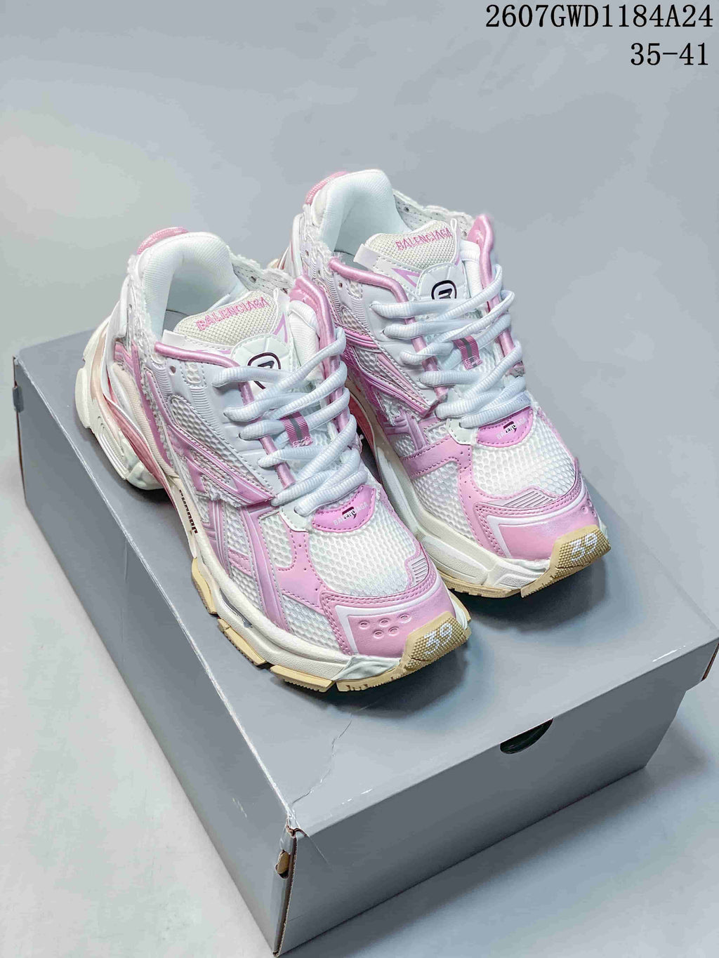Pair of pink and white Balenciaga Runner sneakers displayed on a shoebox.