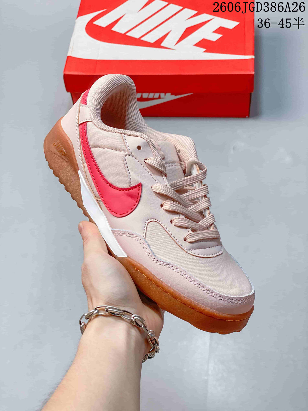Three-quarter side view of the sneaker showing the pale pink upper, red side branding, white midsole section and gum outsole.