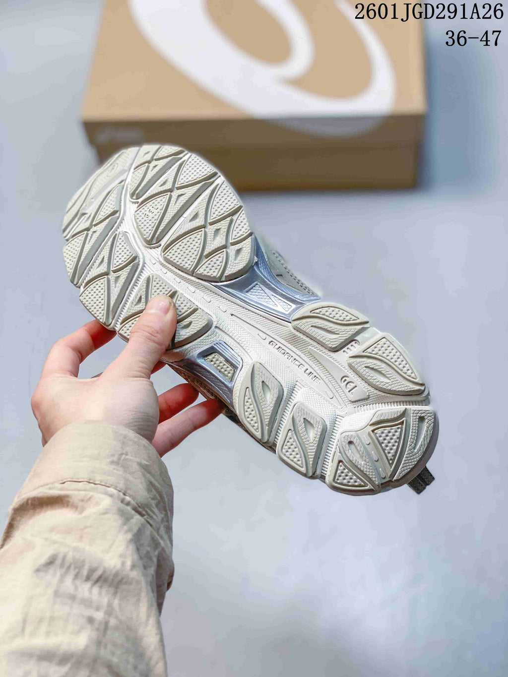 Close view of the textured outsole and tread pattern of the gray and white sneakers.