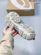 Close view of the textured outsole and tread pattern of the gray and white sneakers.