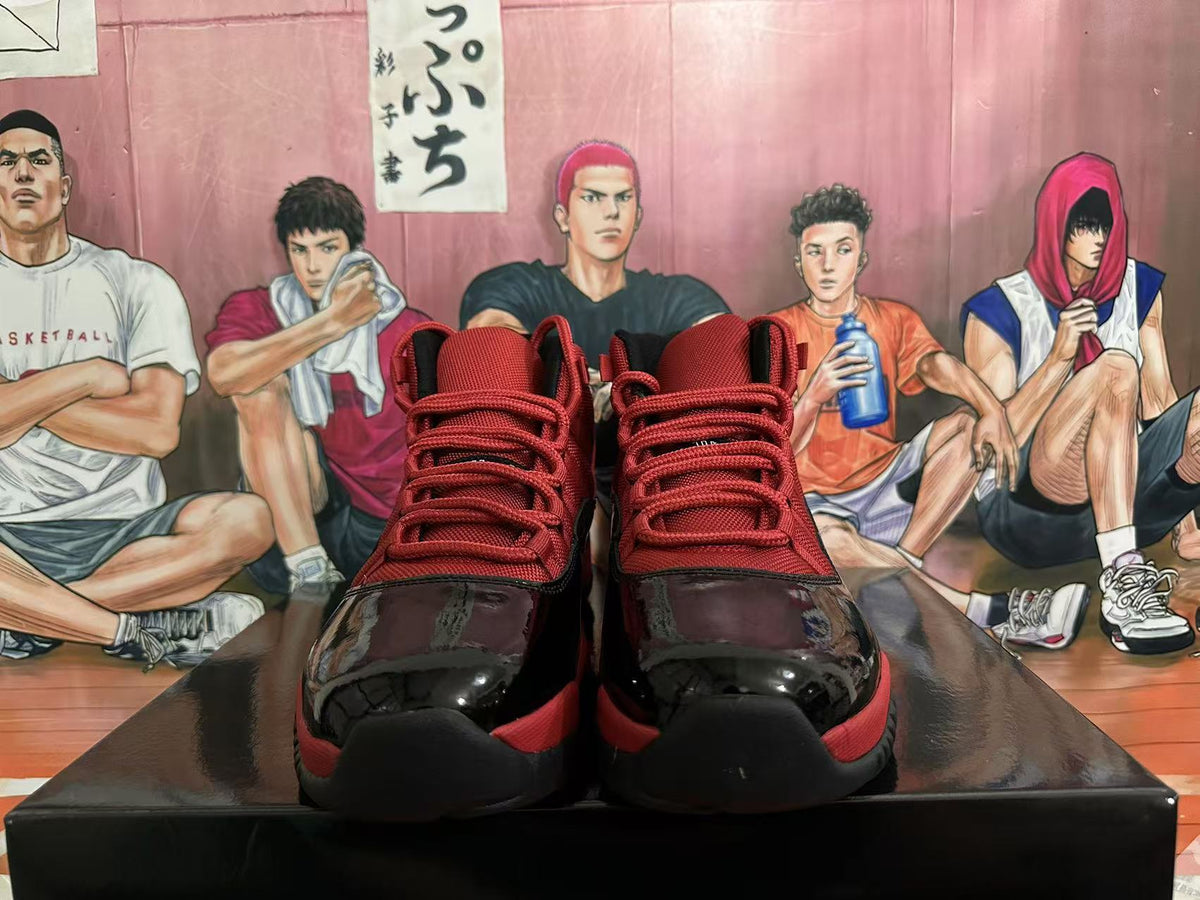Front view of black and red high-top sneakers with red laces, glossy black toe panels, and black soles.