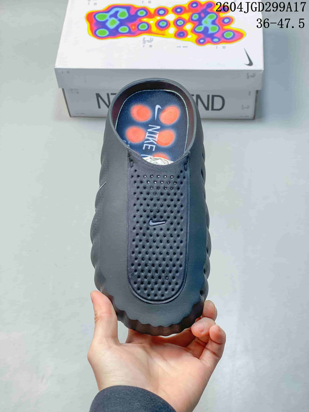 Top view of the dark Nike Mind slide showing the perforated toe panel, Nike branding, and orange details in the footbed.