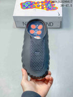 Top view of the dark Nike Mind slide showing the perforated toe panel, Nike branding, and orange details in the footbed.