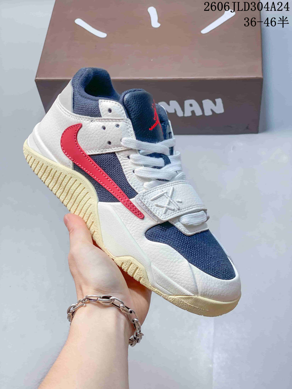 Angled side view of the low-top sneaker with cream, navy, and red details