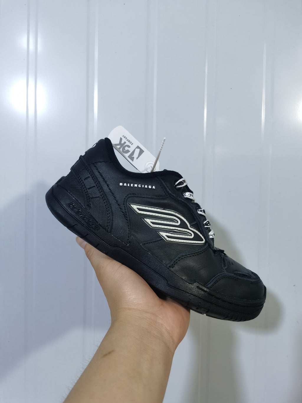 Black Balenciaga sneaker shown from an angled side view with layered panels, contrasting side detail, and branded laces.