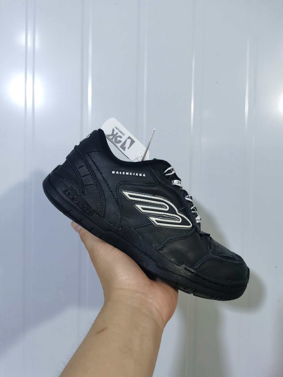 Black Balenciaga sneaker shown from an angled side view with layered panels, contrasting side detail, and branded laces.