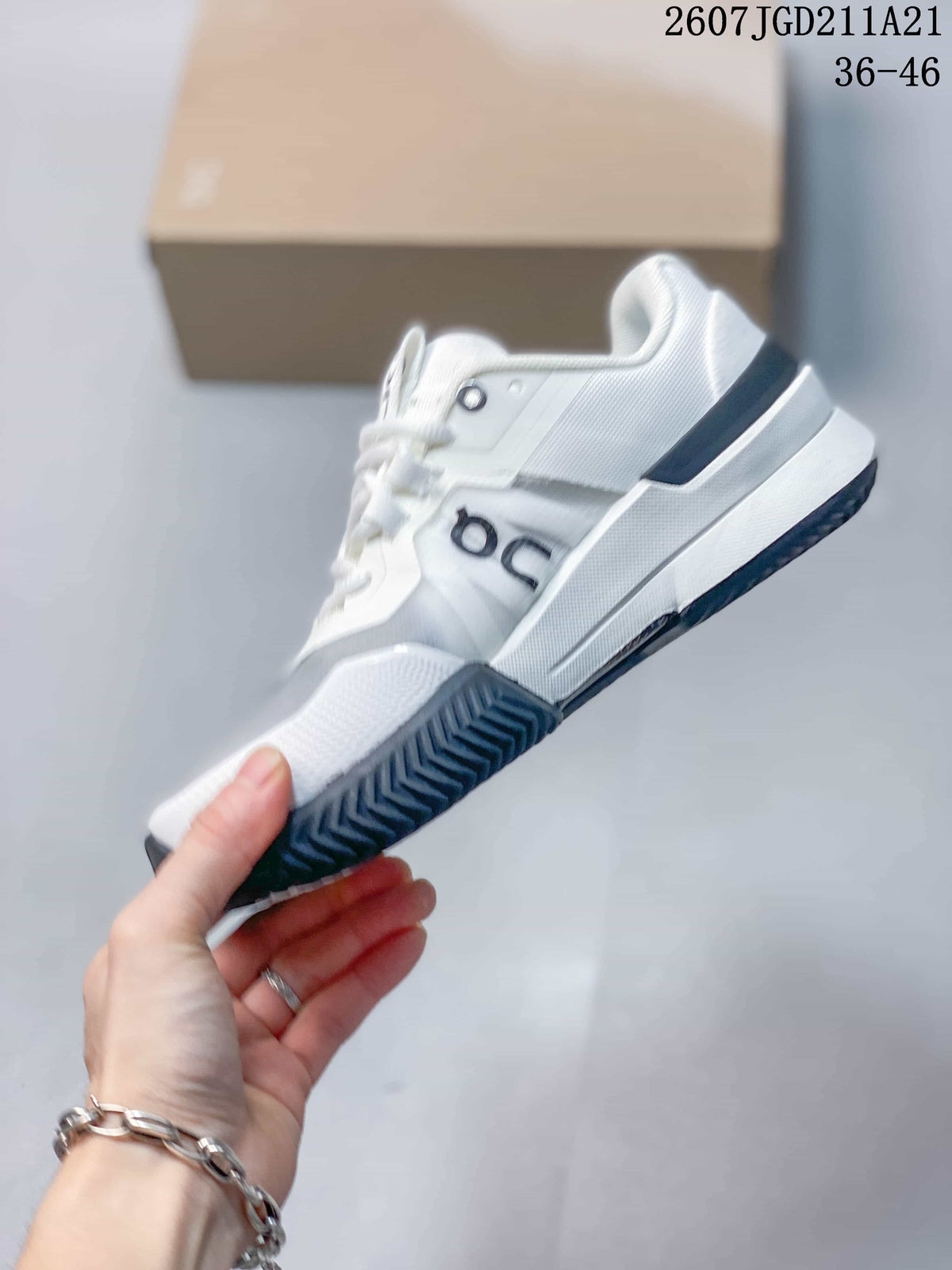 Side profile of the white On sneaker showing layered panels, navy accents, and textured outsole.