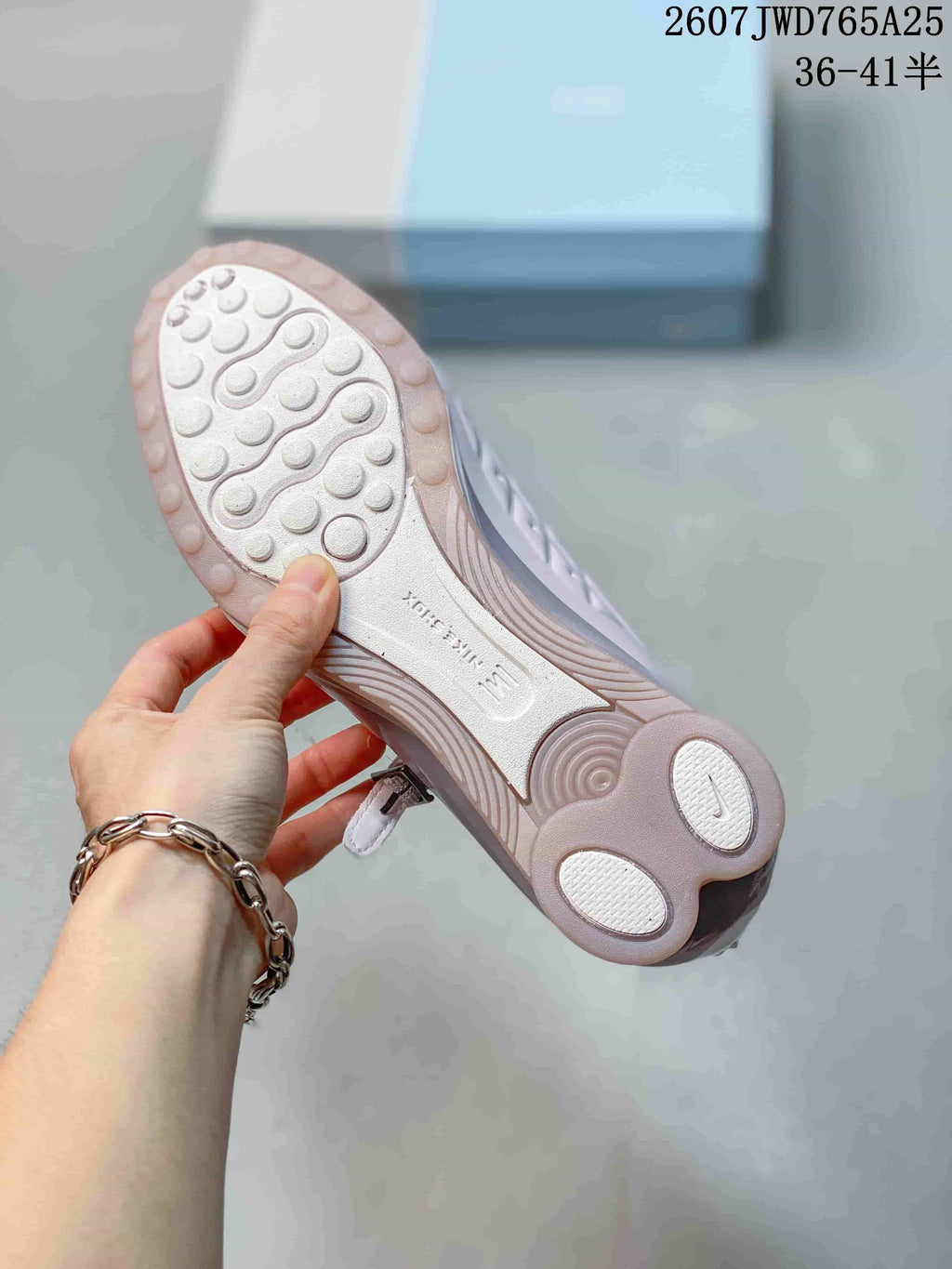 Underside view showing the textured outsole and circular traction elements of the pearl pink sneaker.