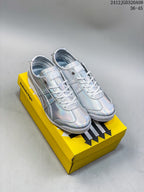 Pair of silver iridescent Onitsuka Tiger low-top sneakers displayed on a yellow shoebox.