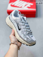 Angled side view of the white and silver Nike P-6000 sneaker with dark Swoosh branding and textured outsole.