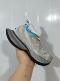 Close-up angled view of grey and blue New Balance Circuit sneakers with mesh panels, layered overlays, white laces, and a black outsole.
