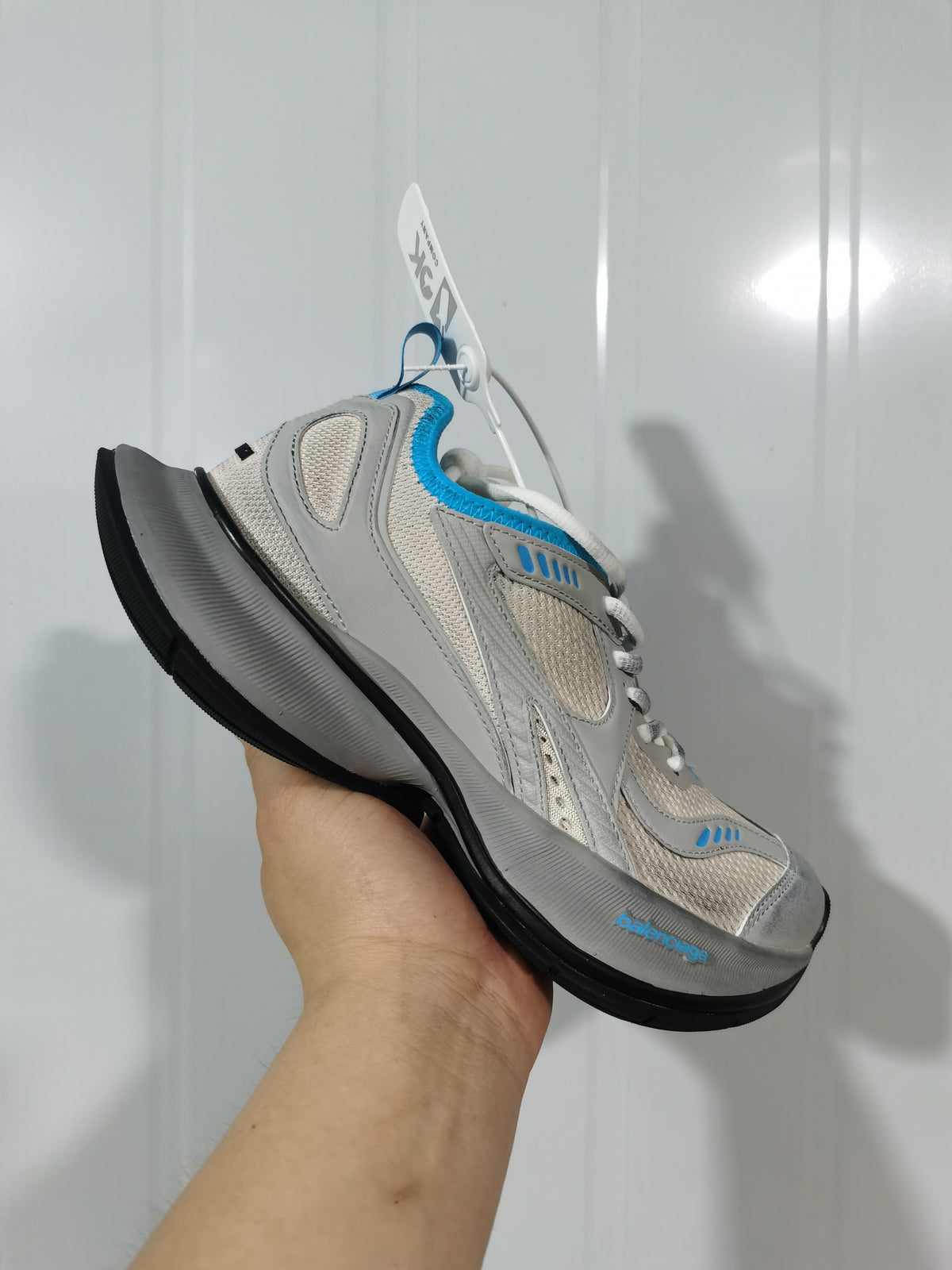 Close-up angled view of grey and blue New Balance Circuit sneakers with mesh panels, layered overlays, white laces, and a black outsole.