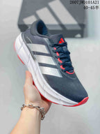 Angled side view of the sneaker showing the dark gray upper, white side stripes, sculpted white midsole, and red outsole.