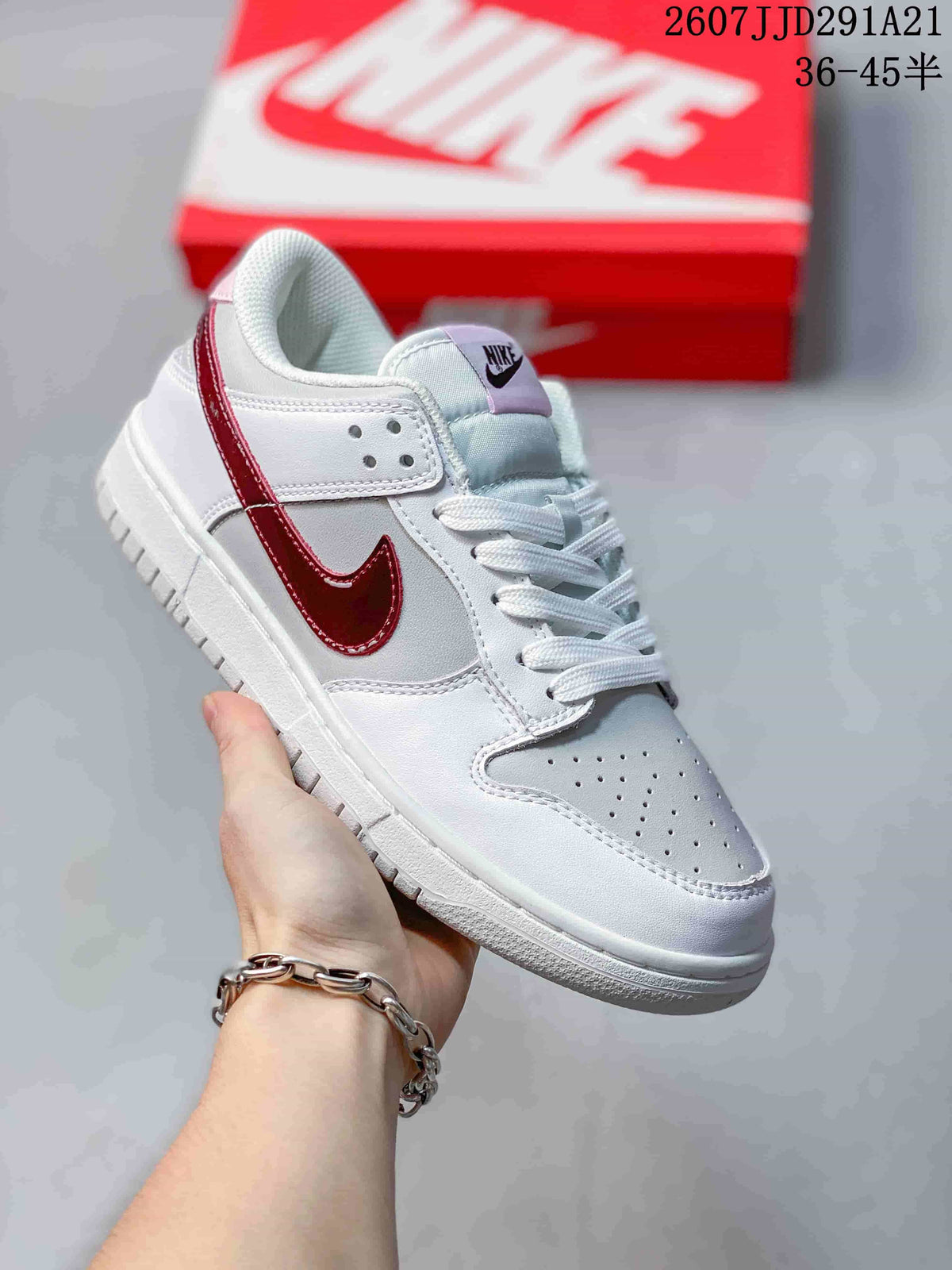 Angled side view showing the white and red colorway, lace-up construction, perforated toe box, and low-top shape.
