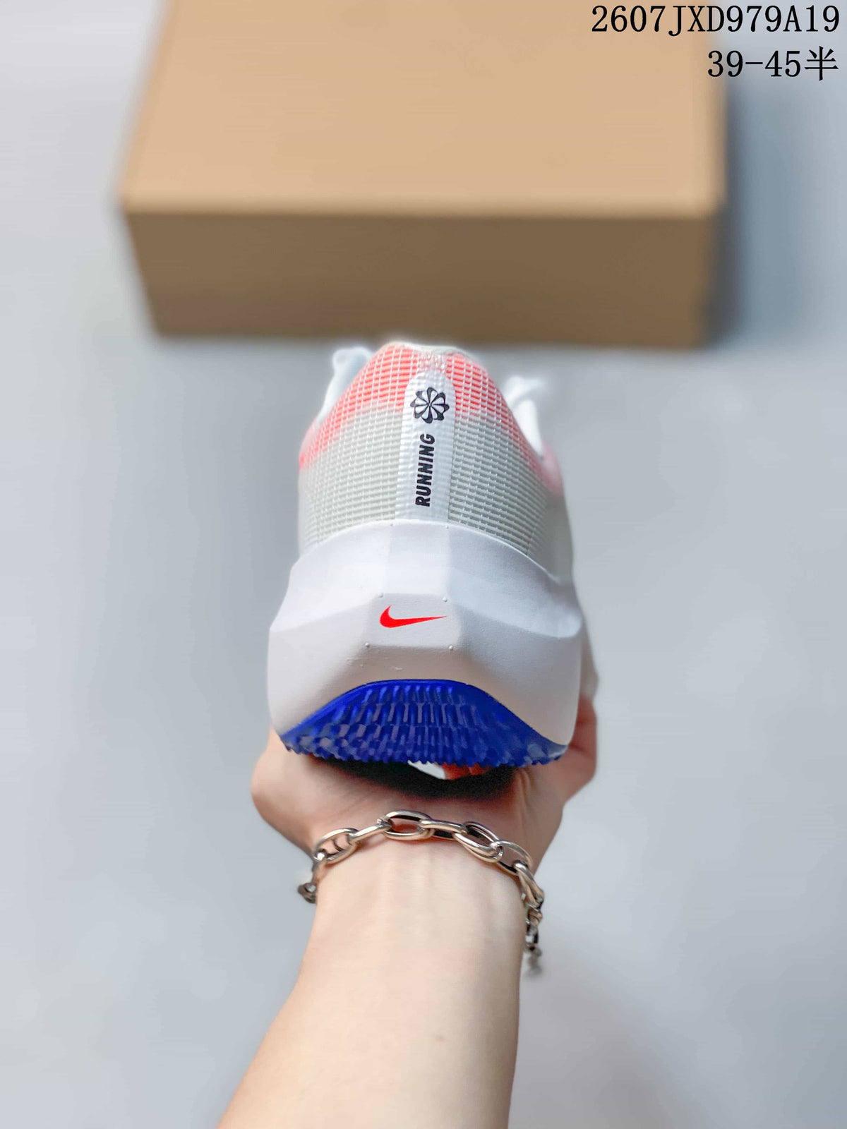 Rear view of a white Nike running shoe with coral heel detailing, a red Swoosh and blue outsole rubber.