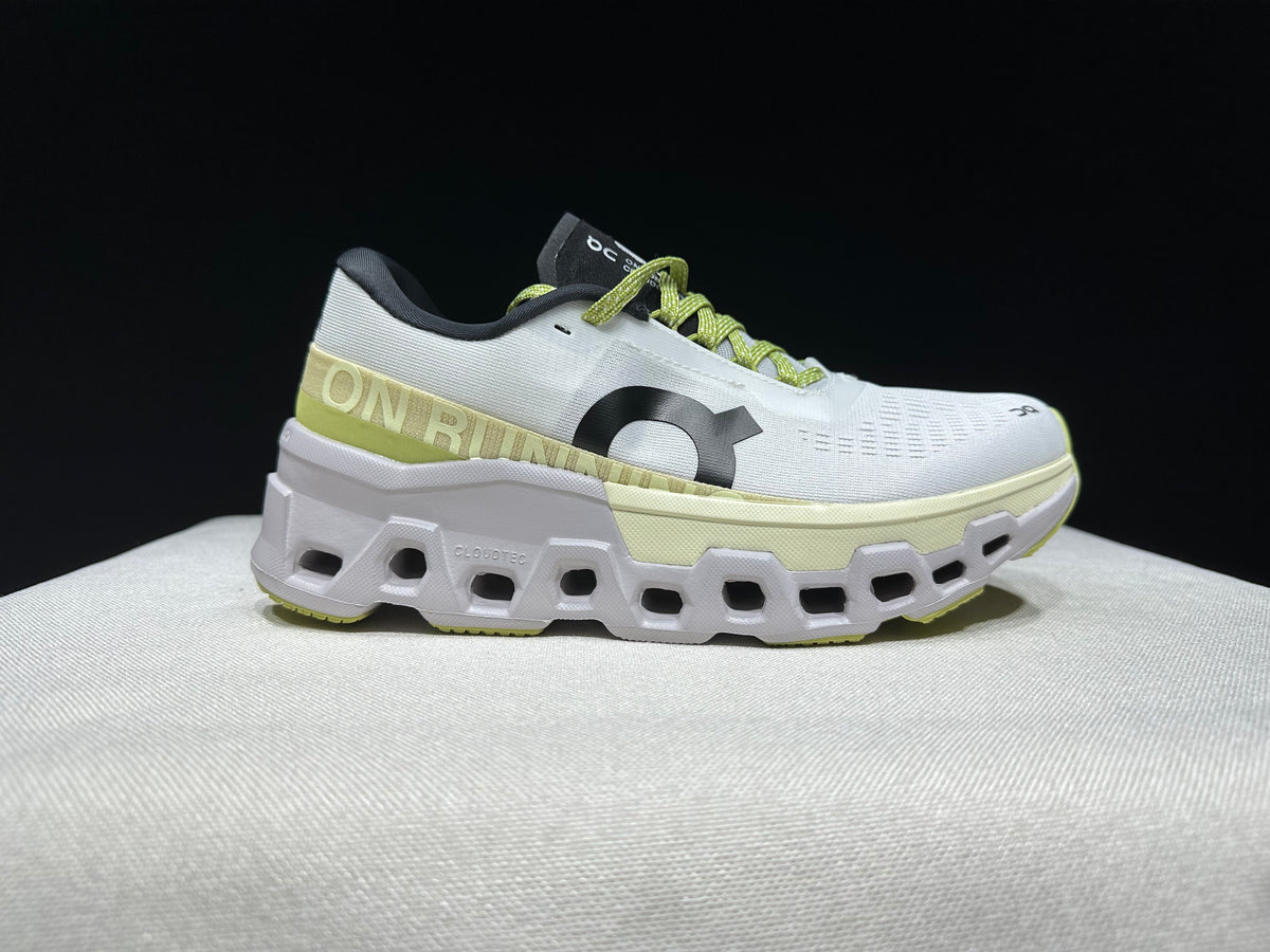 Side profile of a white Cloudmonster 2 shoe with lime accents and a chunky sole.
