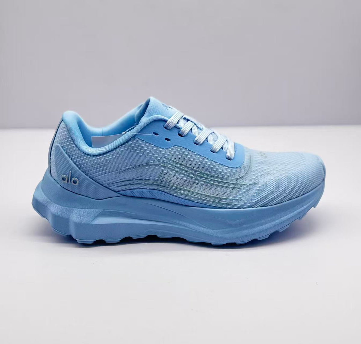 Side view of a light blue Alo sneaker showing the textured upper, layered side detail and sculpted sole.