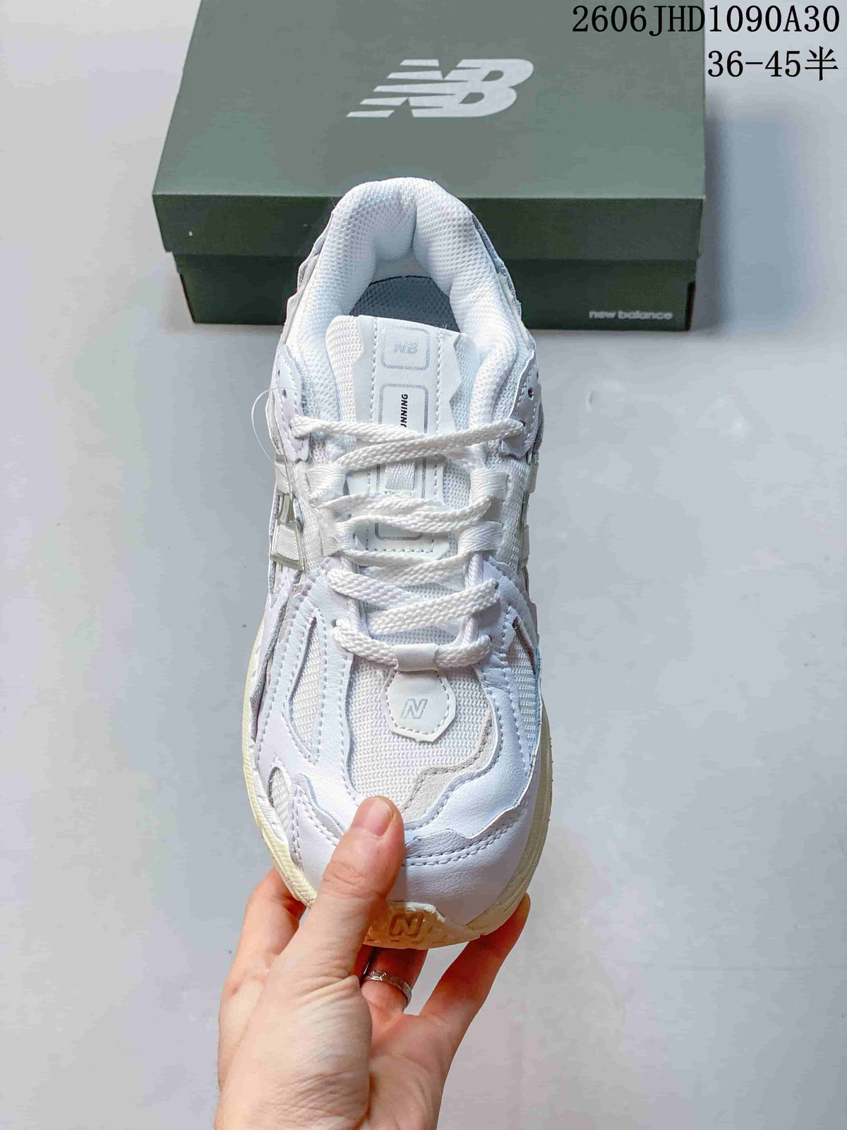 Top view of a white and silver-toned New Balance M1906R sneaker with white laces and mesh panels.