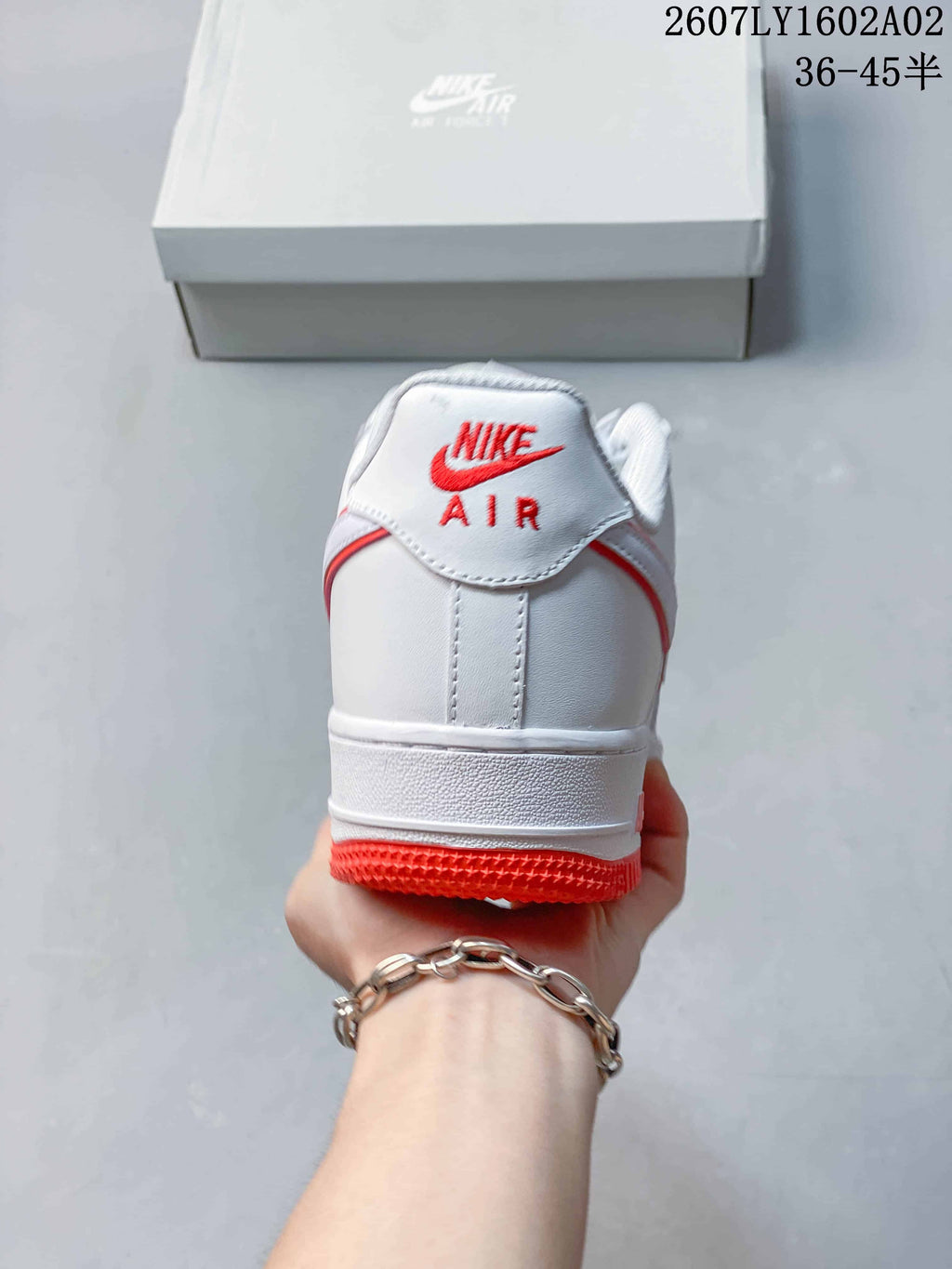 Rear view of a white Nike Air Force 1 ’07 sneaker with red heel accents.