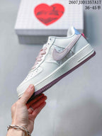 Side profile showing the white upper, pale pink Swoosh accent, blue heel detail and mauve outsole.