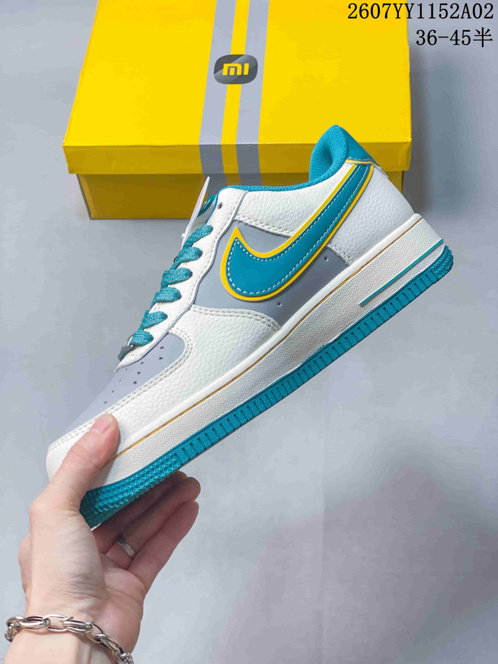 Side view of the sneaker with turquoise and yellow accents and a grey panel