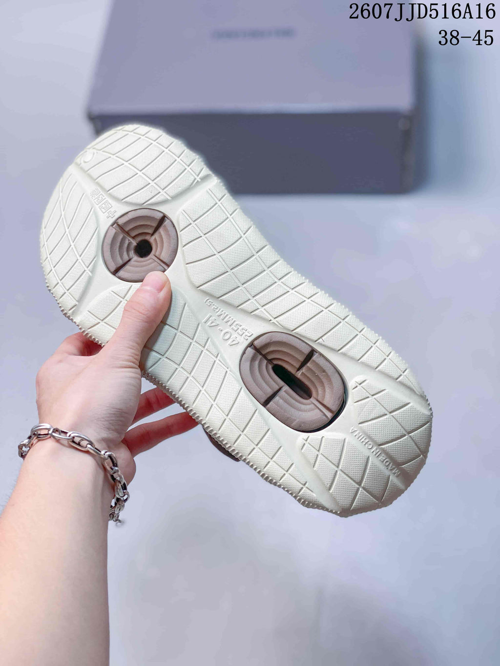 Underside view of the cream slides showing the textured grid outsole and brown circular outsole details.