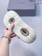 Underside view of the cream slides showing the textured grid outsole and brown circular outsole details.