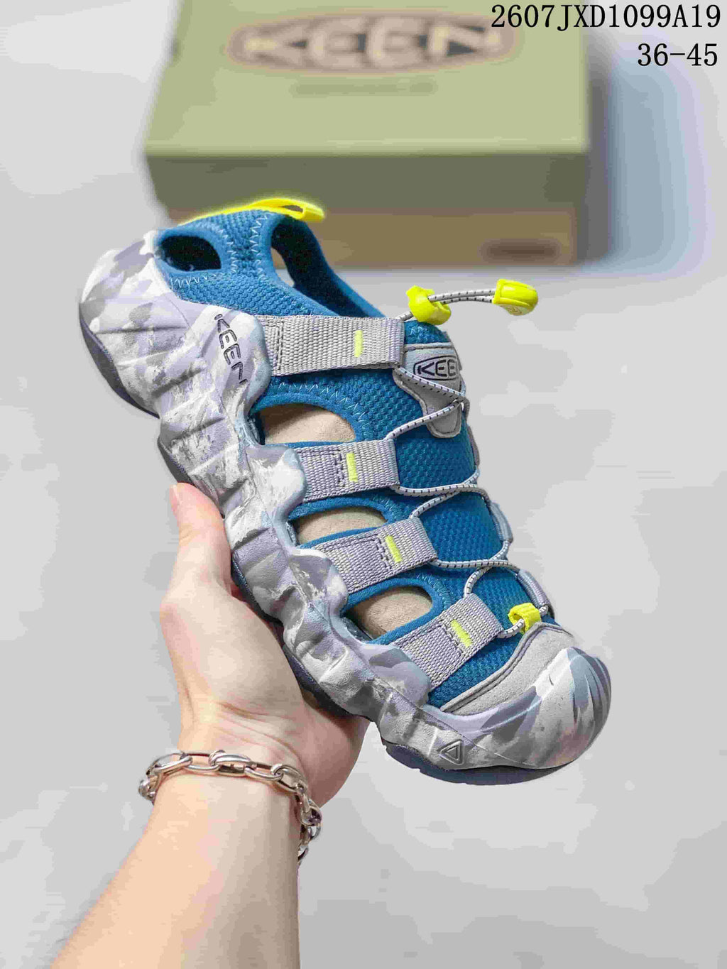 Blue, gray and bright yellow Keen sandal with contrasting straps, quick-lacing hardware and a patterned protective bumper; the image includes the size range 36–45.