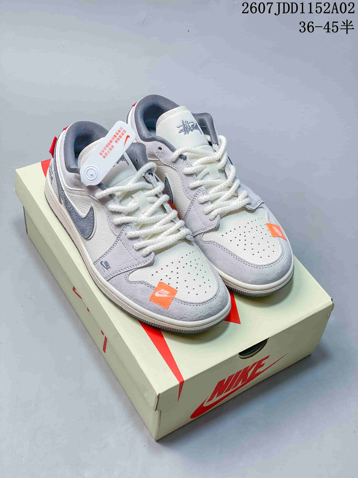 Pair of light gray low-top sneakers with white laces, gray overlays, and small orange accents.