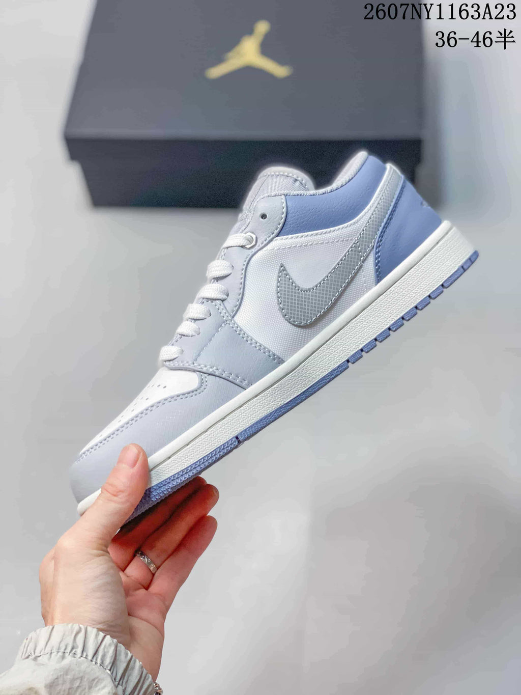 Side profile showing the light grey and white low-top sneaker, textured side panel, and patterned outsole.