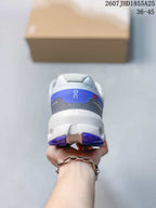 Rear view of the white and blue sneaker showing the padded heel collar, blue heel panel, and segmented outsole.