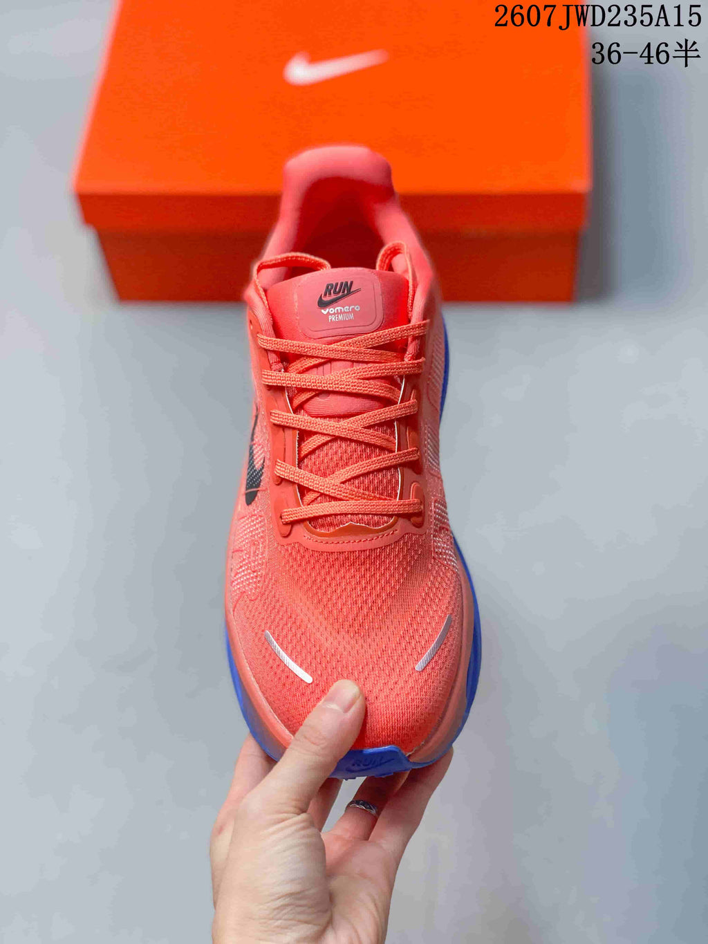 Top view of a coral Nike running shoe with laces, textured toe box, and Vomero Premium tongue branding.