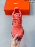 Top view of a coral Nike running shoe with laces, textured toe box, and Vomero Premium tongue branding.