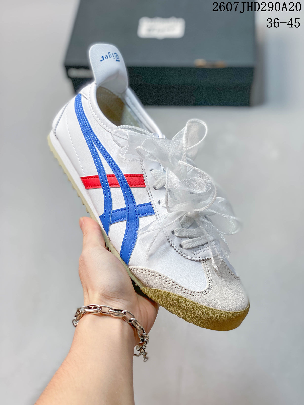 Angled side view of the white sneaker with blue and red stripes and a gum-colored sole.