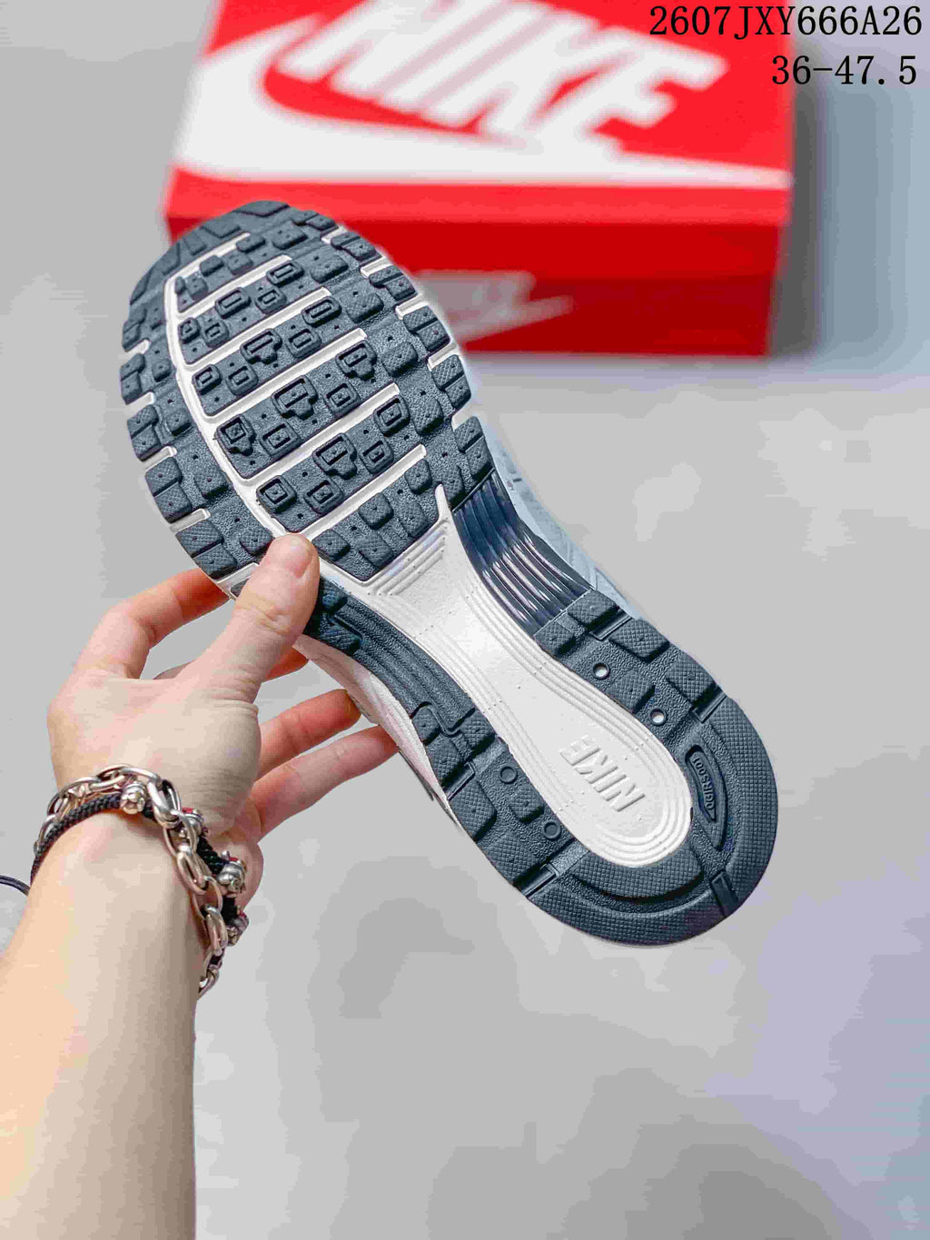 Close view of the sneaker outsole showing black segmented tread and a light central section.