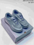 Dark gray Descente low-top running shoes with dial closures, displayed on a box.