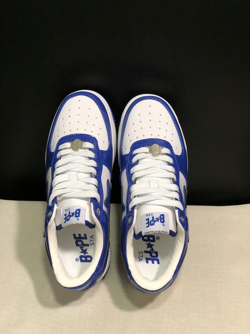 Top view showing the perforated white toe boxes, white laces, blue overlays, and branded insoles.