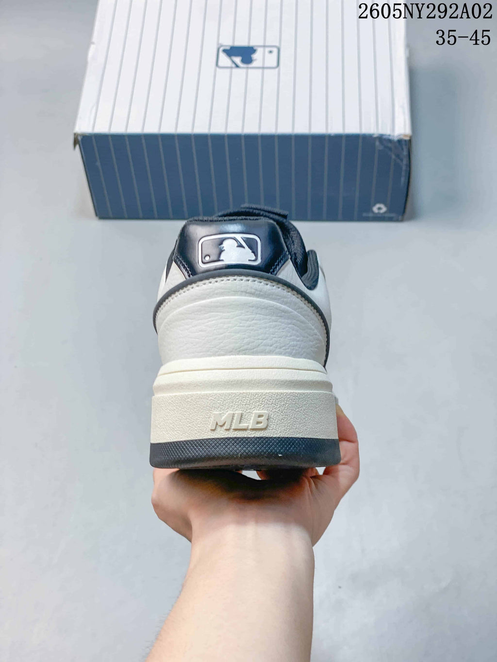 Rear view of the white sneaker showing the padded heel, raised sole, dark outsole section, and MLB heel branding.
