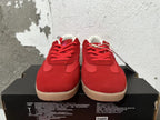 Front view of red lace-up Converse sneakers with pink accents and tan-colored soles.